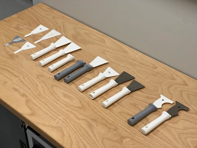Scraping knife handle prototypes and blades laid out for comparison